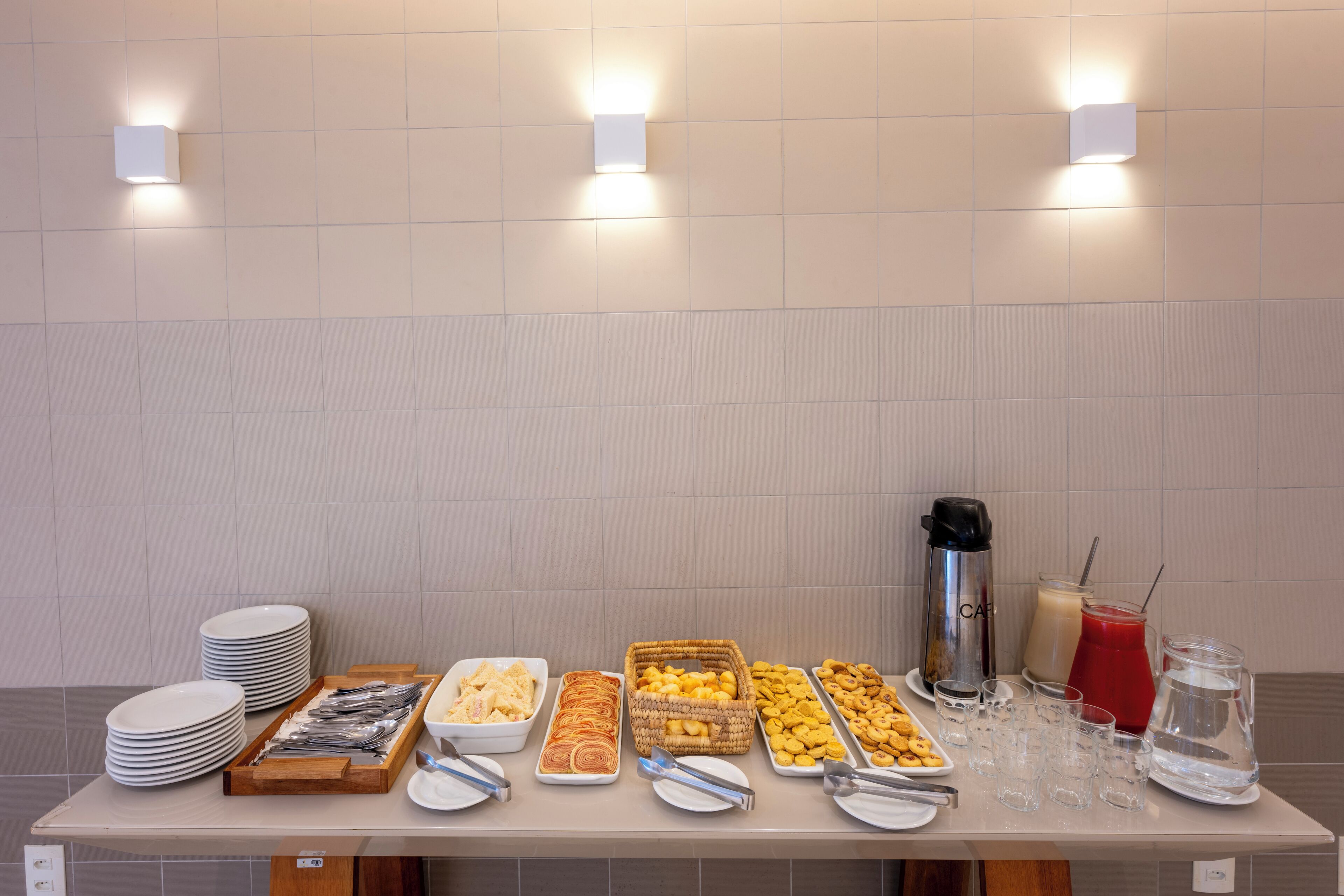 Una mesa de buffet con diferentes alimentos y bebidas, incluyendo platos, recipientes y vasos.