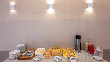 Una mesa de buffet con diferentes alimentos y bebidas, incluyendo platos, recipientes y vasos.