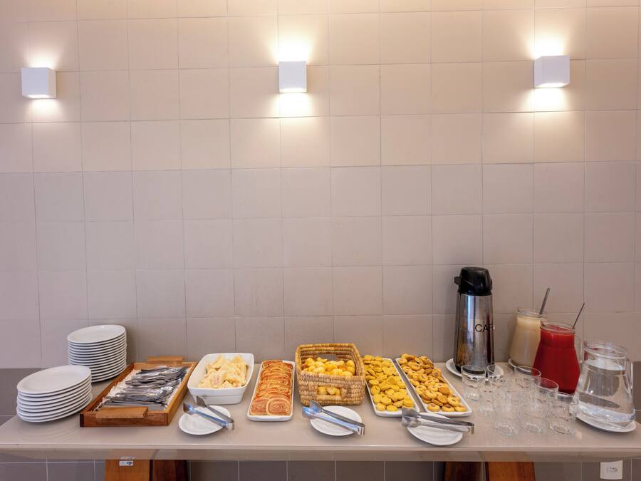 Una mesa de buffet con diferentes alimentos y bebidas, incluyendo platos, recipientes y vasos.