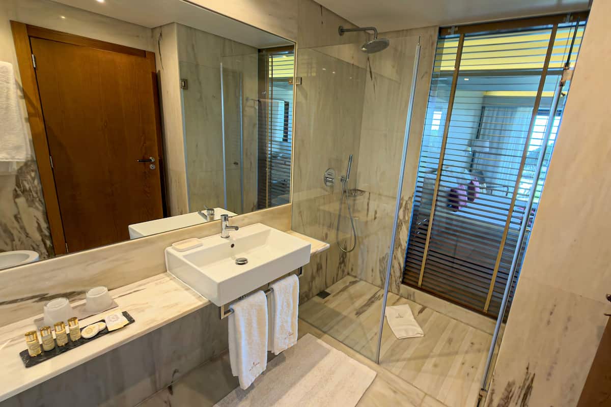 A modern bathroom with a glass shower enclosure, a white sink, and a large mirror.
