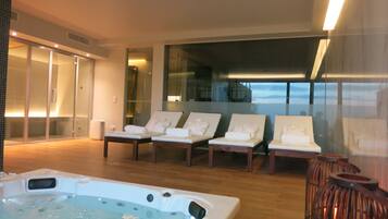 Relax in style with a hot tub and lounge chairs, offering a serene view of the outdoors.