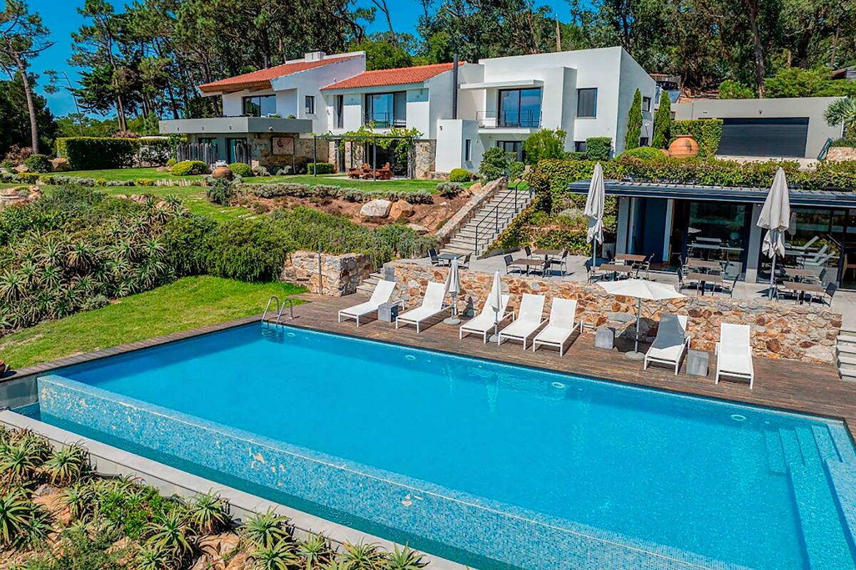 A modern two-story house with a swimming pool, outdoor seating, and a landscaped garden.