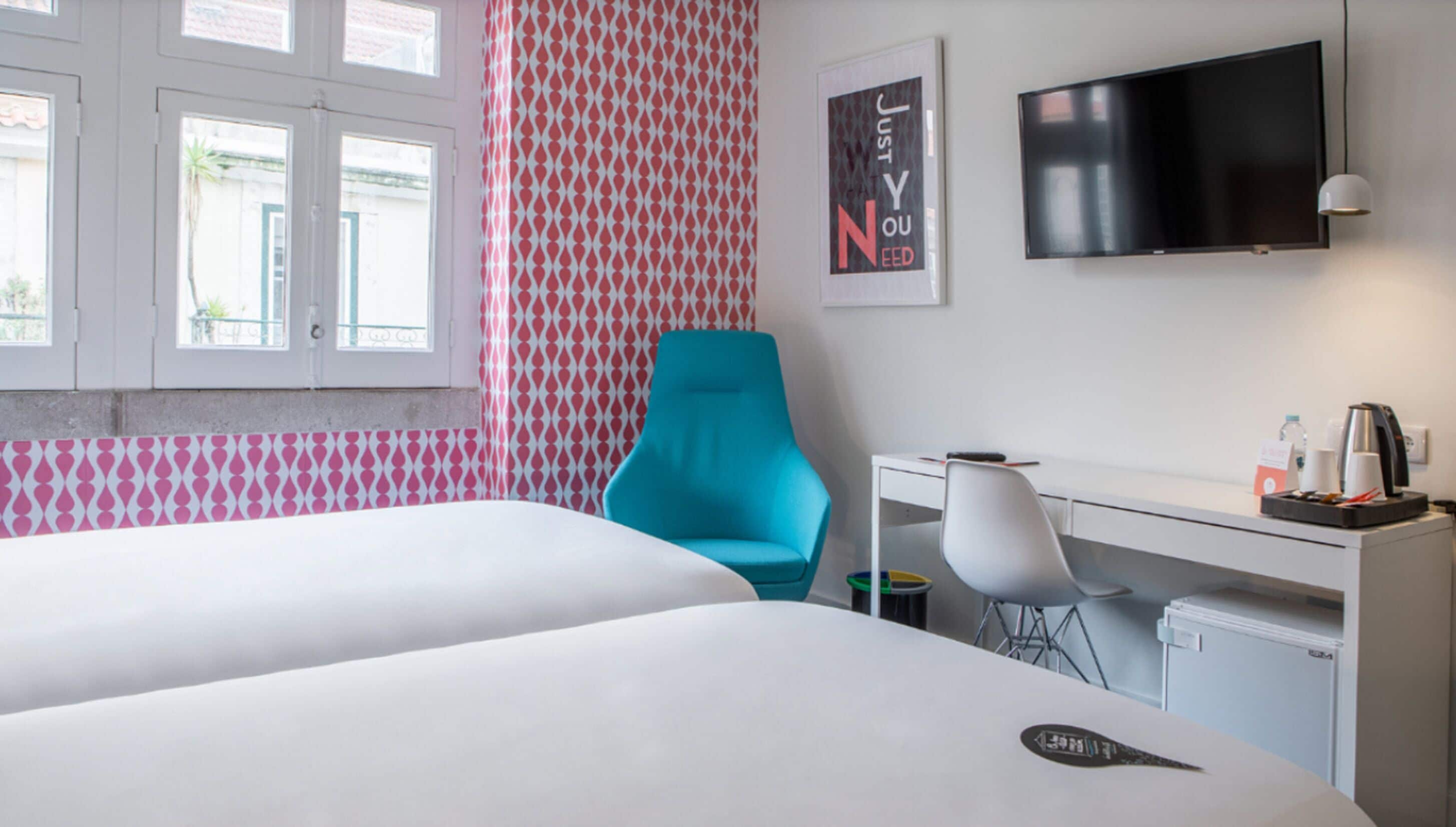 Een hotelkamer met een bed, een bureau, een stoel, een televisie en een behang met patroon.