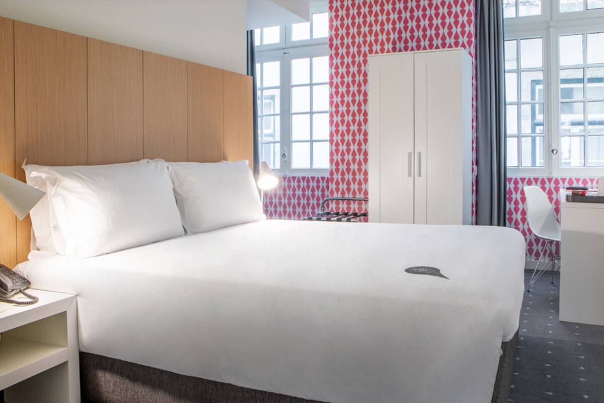 Ein Hotelzimmer mit einem großen Bett, einem Schreibtisch, einem Kleiderschrank und einem Fenster mit Blick.