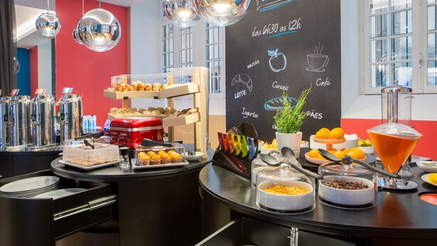 Un buffet de petit-déjeuner proposant une variété de plats, avec un menu écrit à la craie, le tout dans une pièce lumineuse dotée de grandes fenêtres.