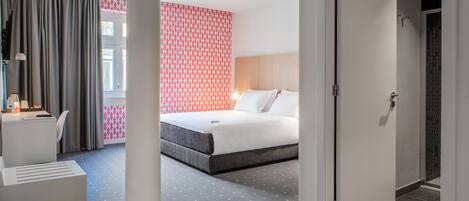 Una habitación de hotel moderna con cama, escritorio y zona de ducha.
