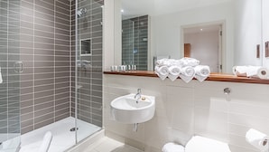 Un baño moderno con cabina de ducha de vidrio, un lavabo blanco y un espejo sobre él.