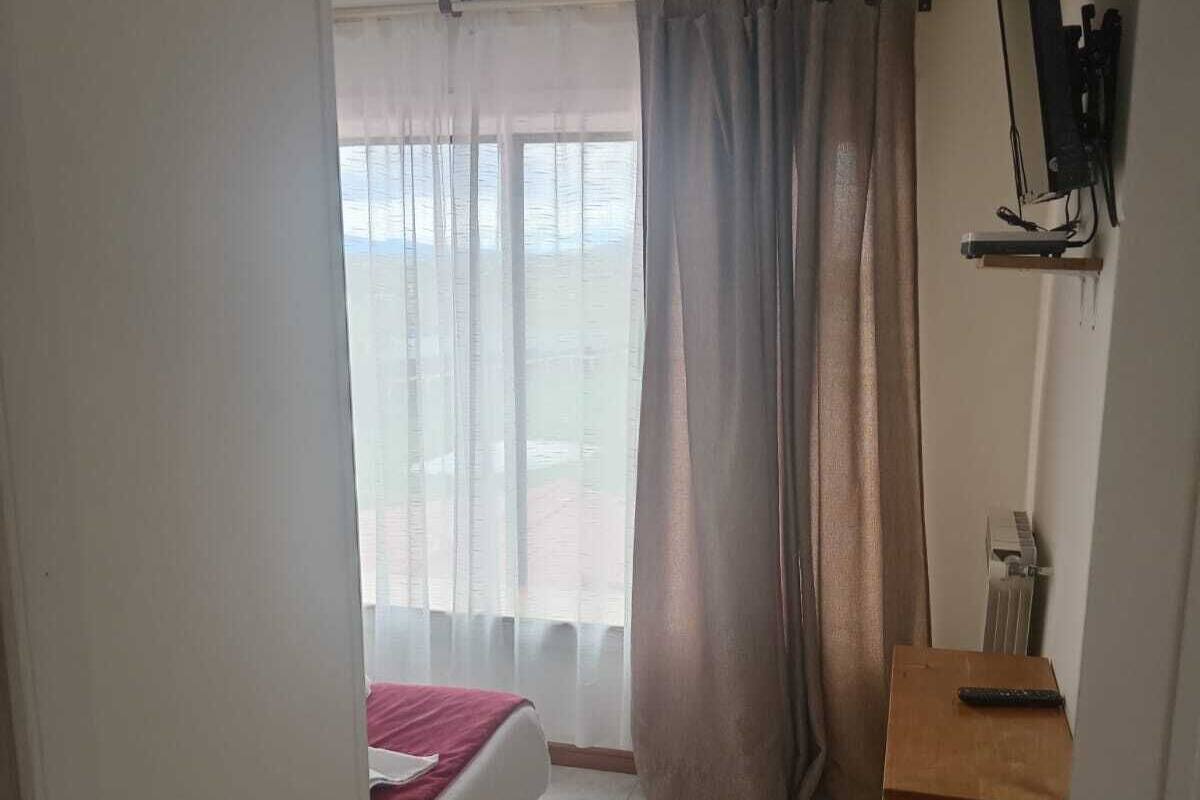 Una habitación de hotel con una cama, un escritorio, un televisor y una ventana con cortinas.