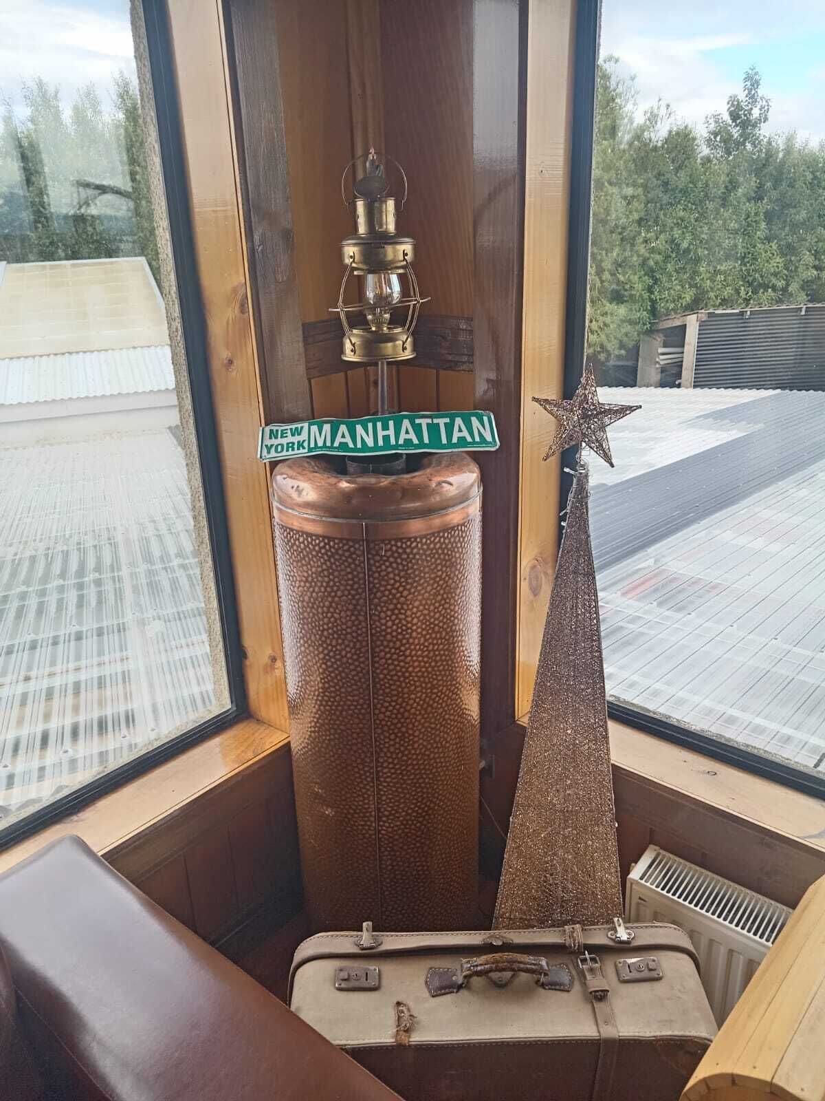 A room with a large window, a Manhattan street sign, a star decoration, and a vintage suitcase.