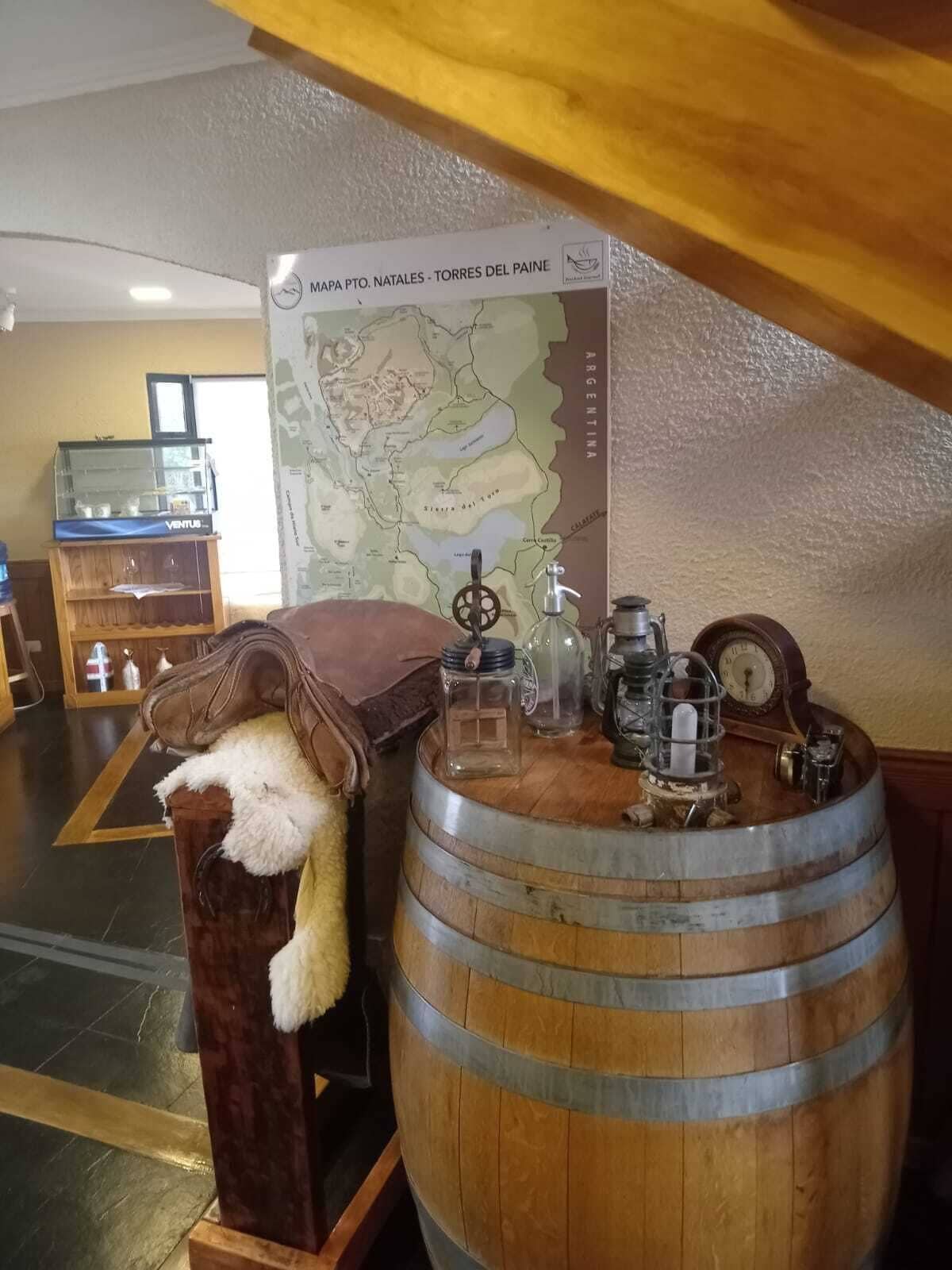 A room with a wooden barrel, a map, and various bottles and jars on a table.