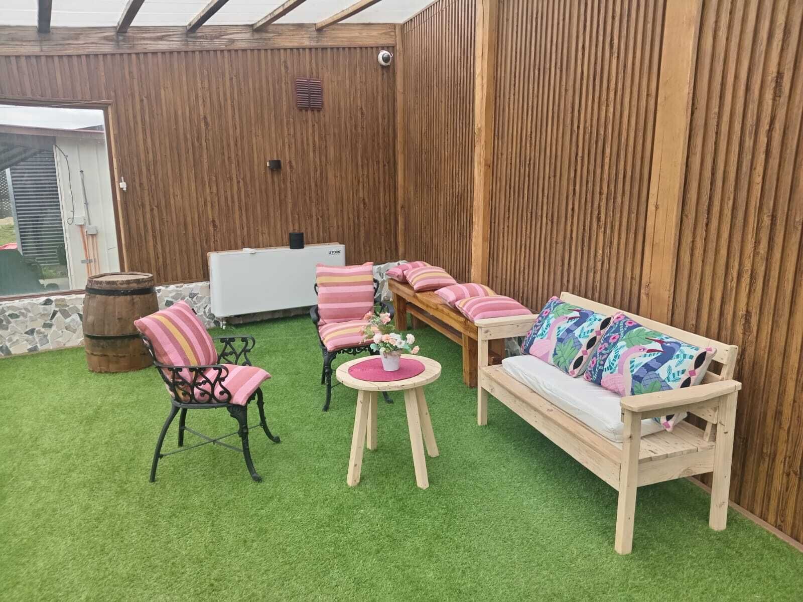 A wooden deck with a sofa, two chairs, a small table, and a decorative barrel.