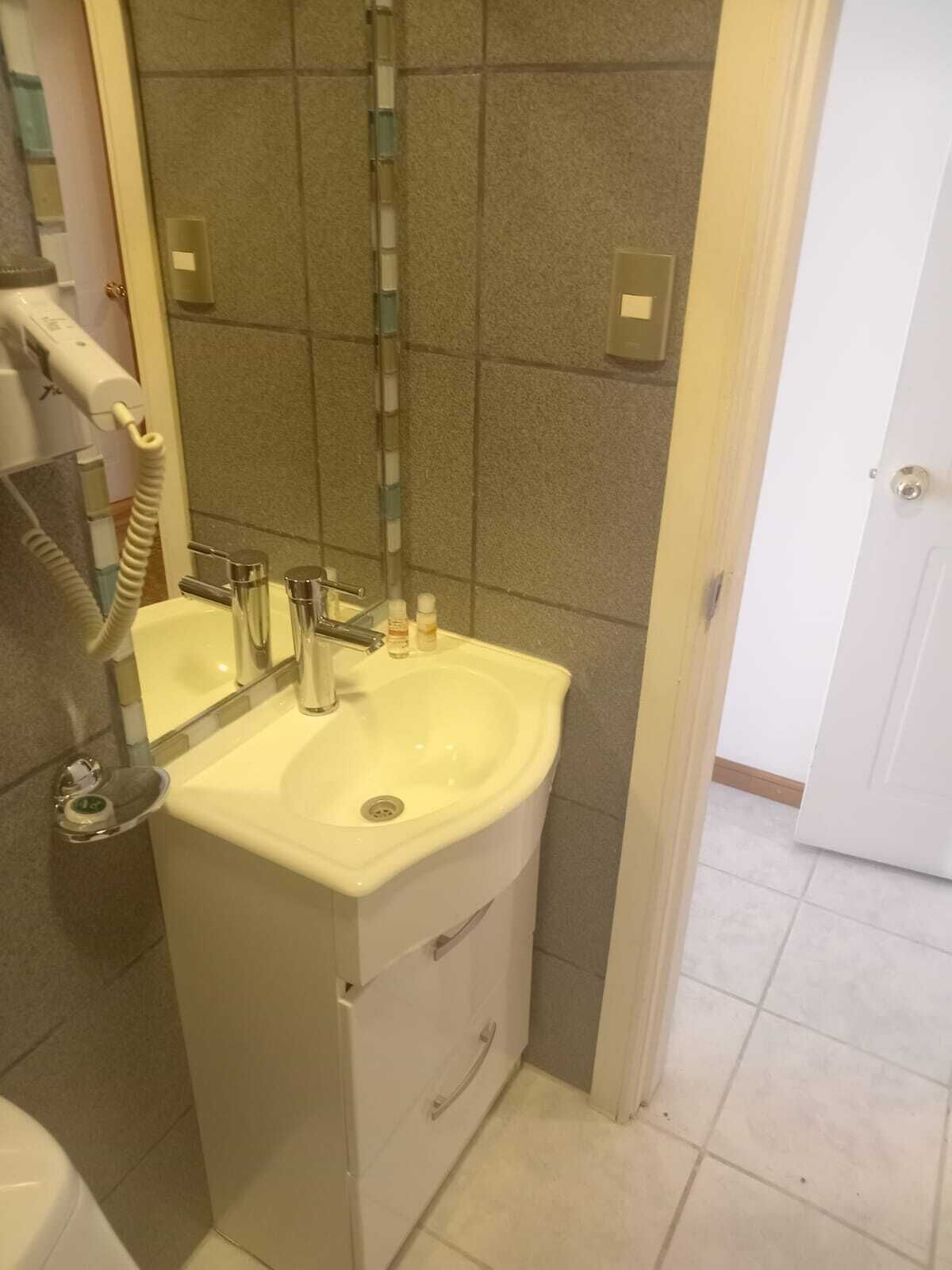 Une salle de bain avec un lavabo blanc, un miroir et un porte-serviettes.