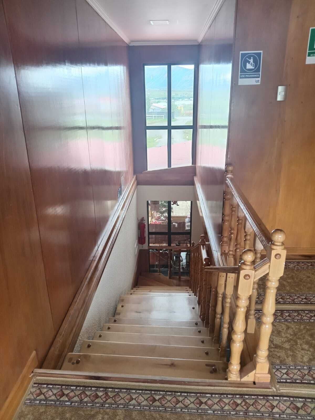 Una escalera de madera con barandilla que lleva a una puerta con vista a una montaña y un edificio.