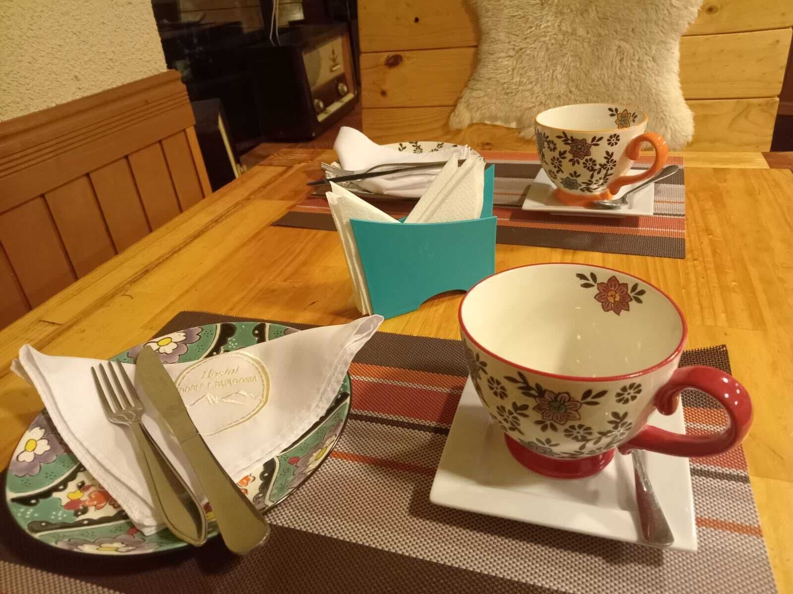 A dining table set with a plate, a cup, a bowl, and a napkin holder.