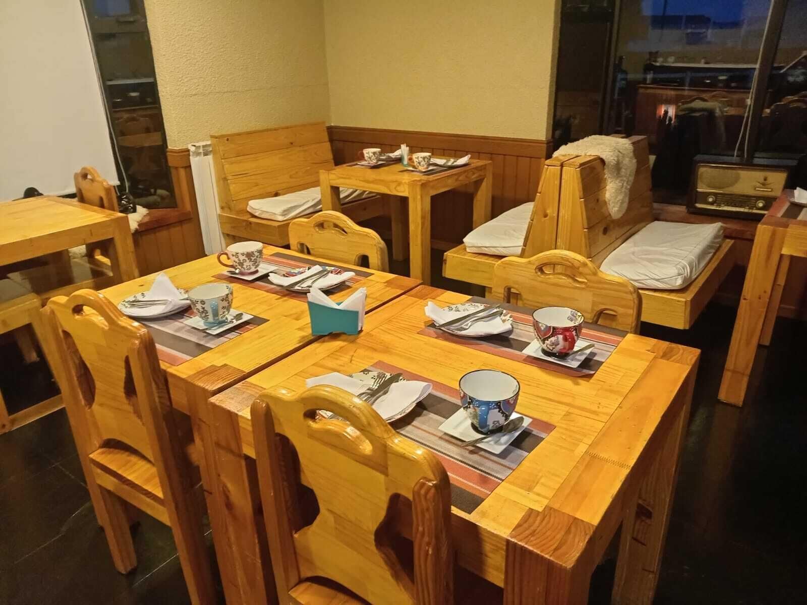 A dining area with wooden furniture, including tables and chairs, and a small table with a radio.