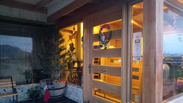 Een hotelentree met een houten deur, een kerstboom en een bordje dat Visa accepteert.