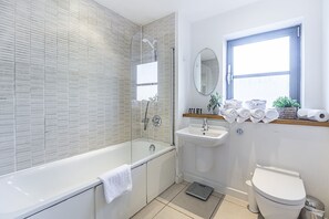 A modern bathroom with a bathtub, sink, and toilet.