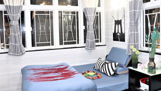 A modern living room with a blue sofa, striped pillows, and a decorative red plant arrangement. - Metrocity Lounge (Kowloon)