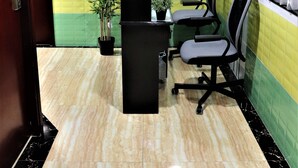 A reception area with a marble floor, a reception desk, two office chairs, a potted plant, and a wall with a floral pattern. - Metrocity Lounge (Kowloon)