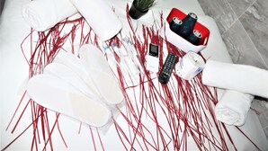 A bathroom with a white bathtub, a white towel, a bottle of shampoo, a bottle of conditioner, a black remote control, a red and black phone, and a small potted plant. - Metrocity Lounge (Kowloon)