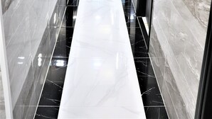 A hallway with glossy black and white marble walls and a shiny black floor. - Metrocity Lounge (Kowloon)