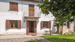 A white building with wooden shutters, a stone pathway, and a grassy area.