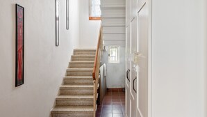 A staircase with a wooden handrail leading to a door with a towel hanging on it.