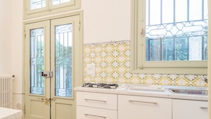 A kitchen with white cabinets, a gas stove, and a window with decorative iron bars. - Torre dell'Orologio Apartment (Padova)