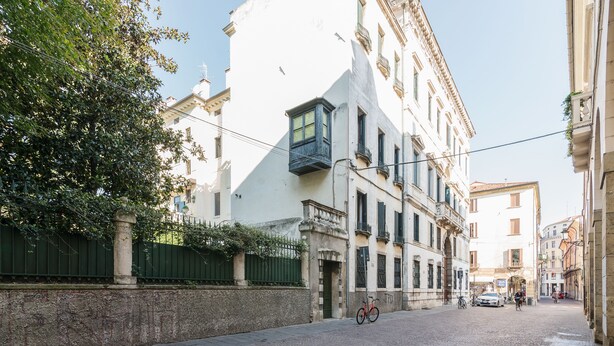 A cobblestone street with a bicycle parked by a building with a balcony. - Torre dell'Orologio Apartment (Padova)