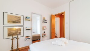 A neatly arranged bedroom with a bed, bedside tables, a wardrobe, and a door leading to another room. - Scrovegni Design Apartment (Padova)