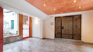 A spacious lobby with a marble floor, a red door, and a decorative metal gate. - Scrovegni Design Apartment (Padova)