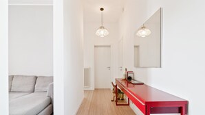 Un couloir avec une console rouge, un miroir et un luminaire.