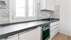 Une cuisine moderne avec des meubles blancs, un plan de travail noir et un four vert.