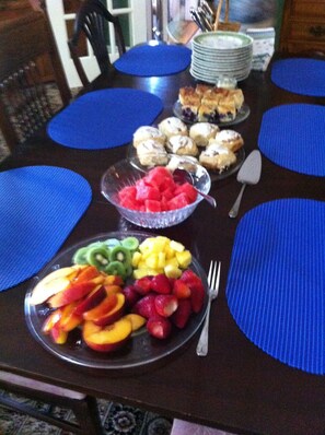 A dining table with blue placemats, a fruit platter, and a bowl of watermelon. - Lantana House (Rockport)