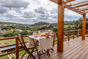 A wooden deck with a table set for breakfast, overlooking a scenic landscape. - Terra Lodge (Mafra)