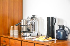 A coffee machine, a black pitcher, and a plate of pastries on a wooden counter. - Flatmilan (Cernusco sul Naviglio)