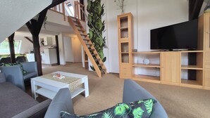 A modern living room with a staircase, a television, and a large plant. - Apartments Villa Ratskopf (Wernigerode)