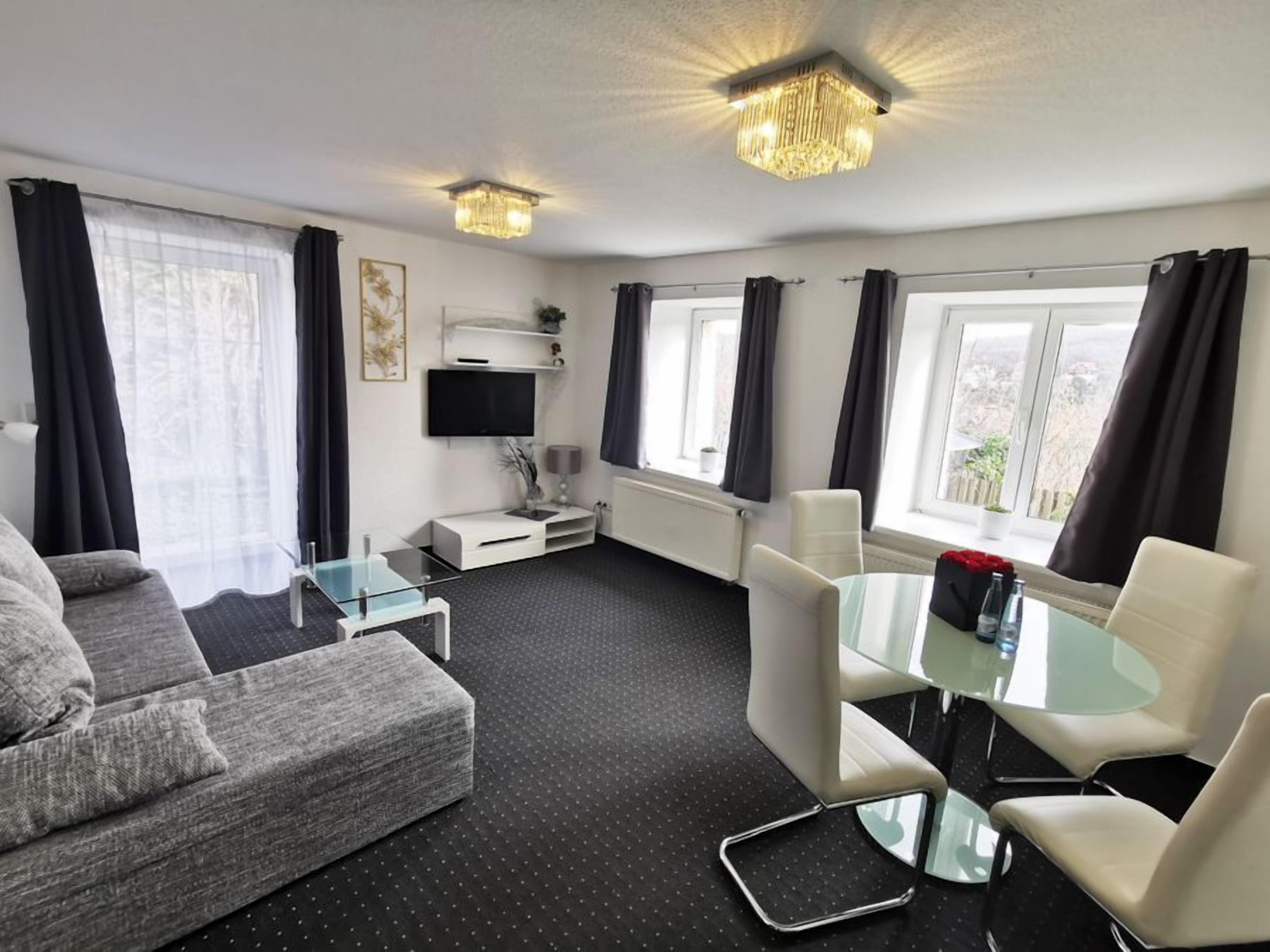 A modern living room with a sofa, a glass coffee table, and a dining area with chairs.