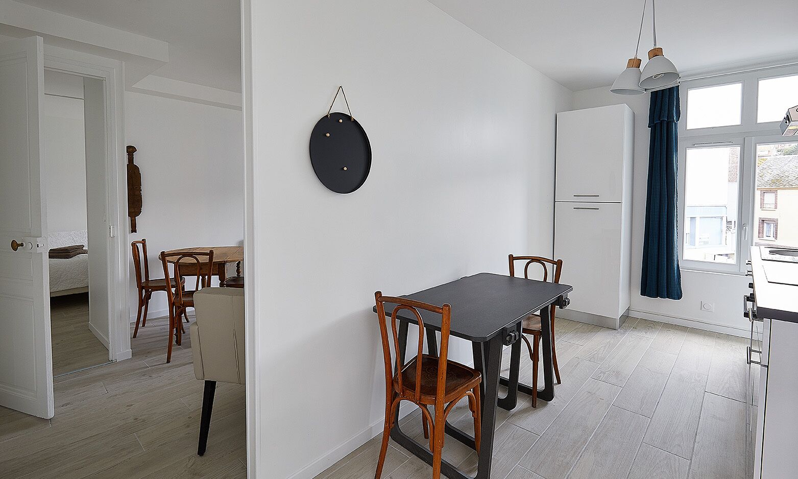 Uma cozinha moderna com mesa e cadeiras, um lustre pendente e vista para o exterior através de uma janela.
