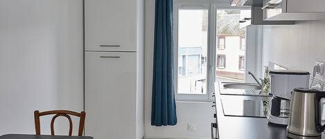Una cocina compacta con ventana, un lavabo y una tetera.