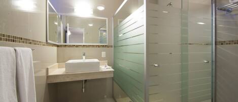 A modern bathroom with a glass-enclosed shower, a sink with a mirror above it, and a towel hanging on the wall.