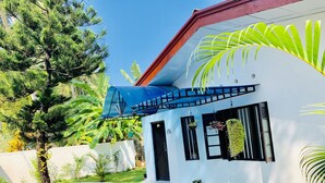 Une maison moderne avec une façade blanche, des fenêtres à encadrement noir et un toit bleu.