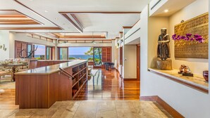 A spacious living area with a wooden bar, a statue, and a view of the ocean.