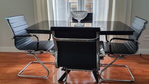 A conference table with a glass top and four black leather chairs with metal frames. - Srecko Centar Apartment (Belgrade)