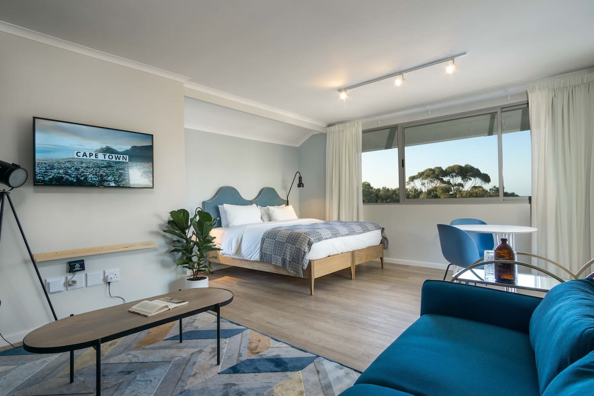 A modern bedroom with a bed, bedside table, and a view of Cape Town.