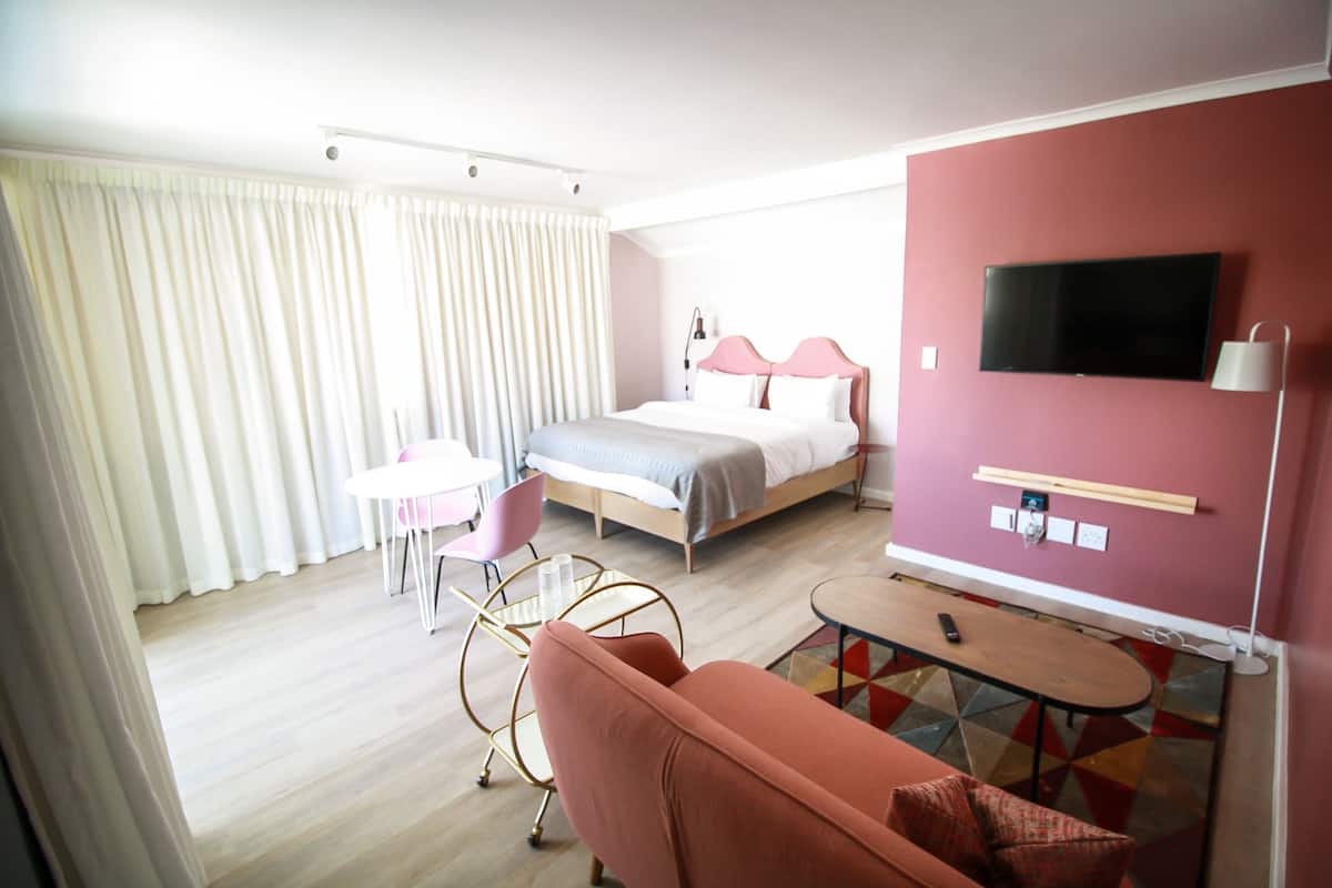 A hotel room with a bed, a TV, a desk, a chair, and a sofa.