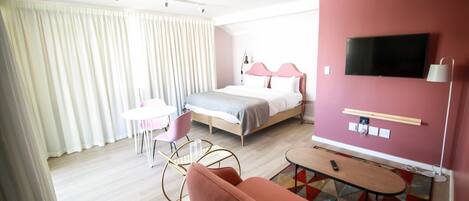 Una habitación de hotel con cama, televisión, escritorio, silla y sofá.