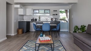A modern kitchen with white cabinets, a microwave, and a dining area with blue chairs.