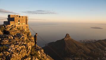 A person standing on a rocky cliff overlooking a city and the ocean.