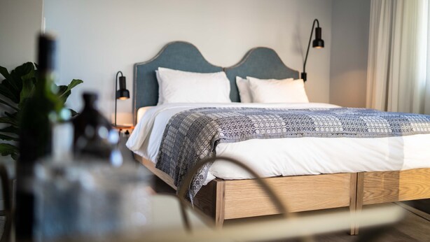 A neatly made bed with a patterned bedspread, a wooden headboard, and bedside lamps.